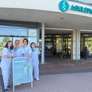 Das Foto zeigt Mitarbeitende vor der Asklepios Harzklinik Goslar, mit dem Foto-Aufsteller für die Speeddating-Tage am 8. Und 9. Mai.