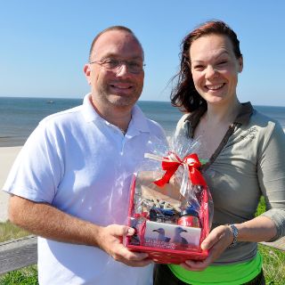 Das Bild zeigt die Jubiläums-Patientin in der Schmerzmedizin mit dem Leitenden Arzt Dr. André Riesmeier am Strand.