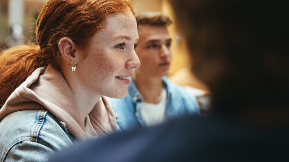 Junges Mädchen lächelt im Freundeskreis