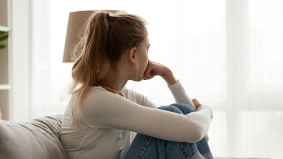 Trauriges Mädchen sitzt am Fenster