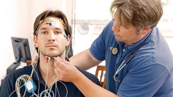 Patient wird bei der Schlafdiagnostik vom behandelnden Arzt verkabelt. Die Schlafanalyse kann bei Stress und Schlafstörungen genauere Aufschluss über die Schlafarchitektur geben.