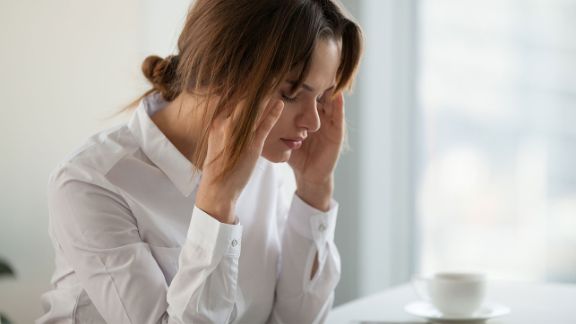 Junge Frau am Tisch hält sich vor Sorgen und Stress die Schläfen Stress, Angst & Depressionen rauben einem die Lebensqualität: Im Fachzentrum Falkenried gehen wir die Probleme gemeinsam an