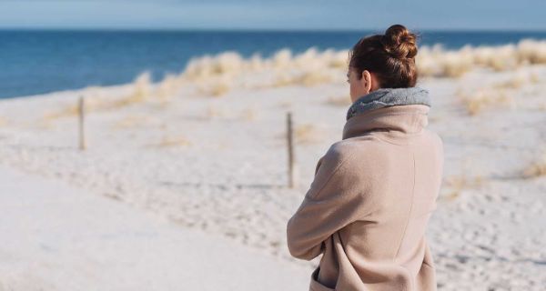 Frau im Mantel steht am Meer und schaut in die Ferne Stress, Angst und Depression im Überblick: Ein Artikel vom Fachzentrum Falkenried