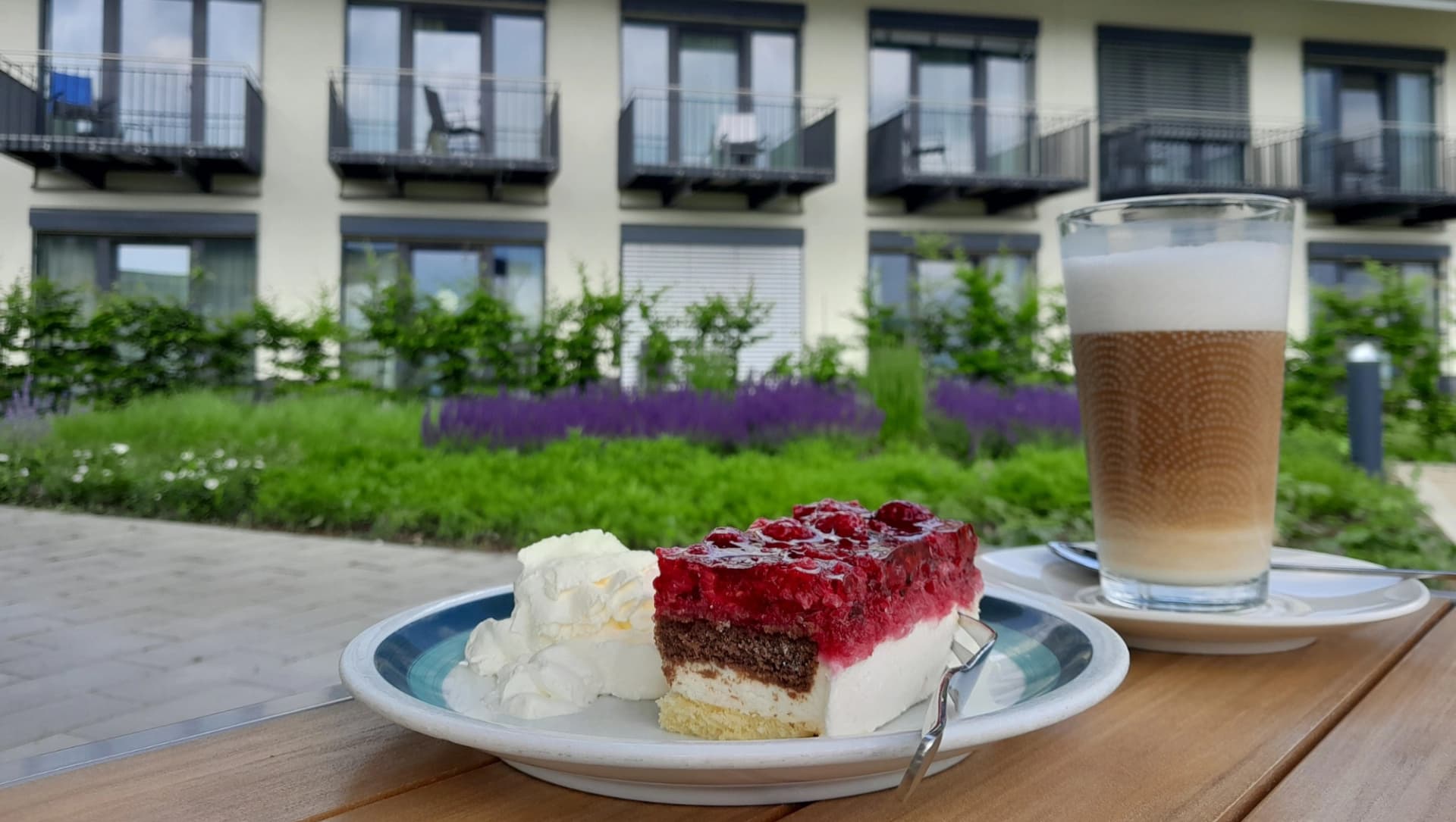 Kaffee und Kuchen im Außenbereich, im Hintergrund ist die Klinik sowie Pflanzen