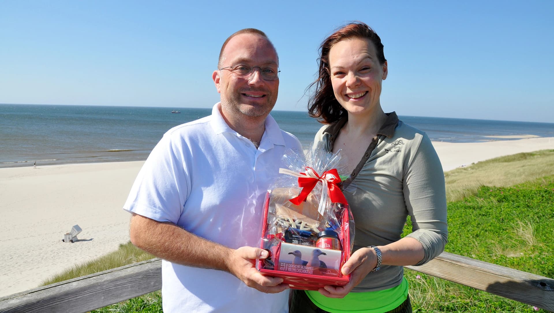 Das Bild zeigt die Jubiläums-Patientin in der Schmerzmedizin mit dem Leitenden Arzt Dr. André Riesmeier am Strand.