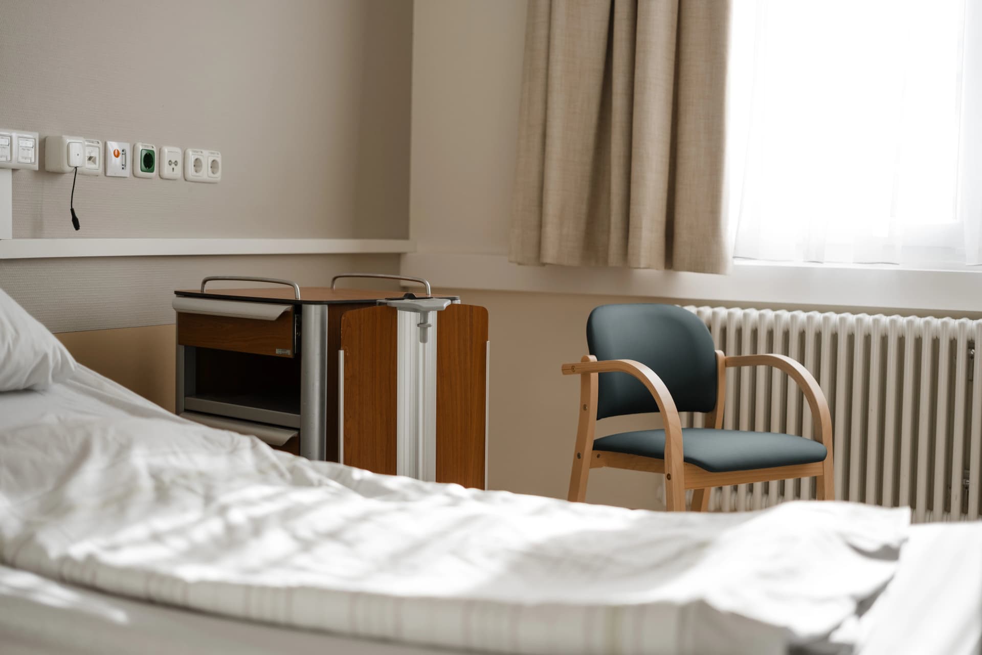 Bild: Inneneinrichtung eines Patientenzimmers mit Bett und Sitzgelegenheit