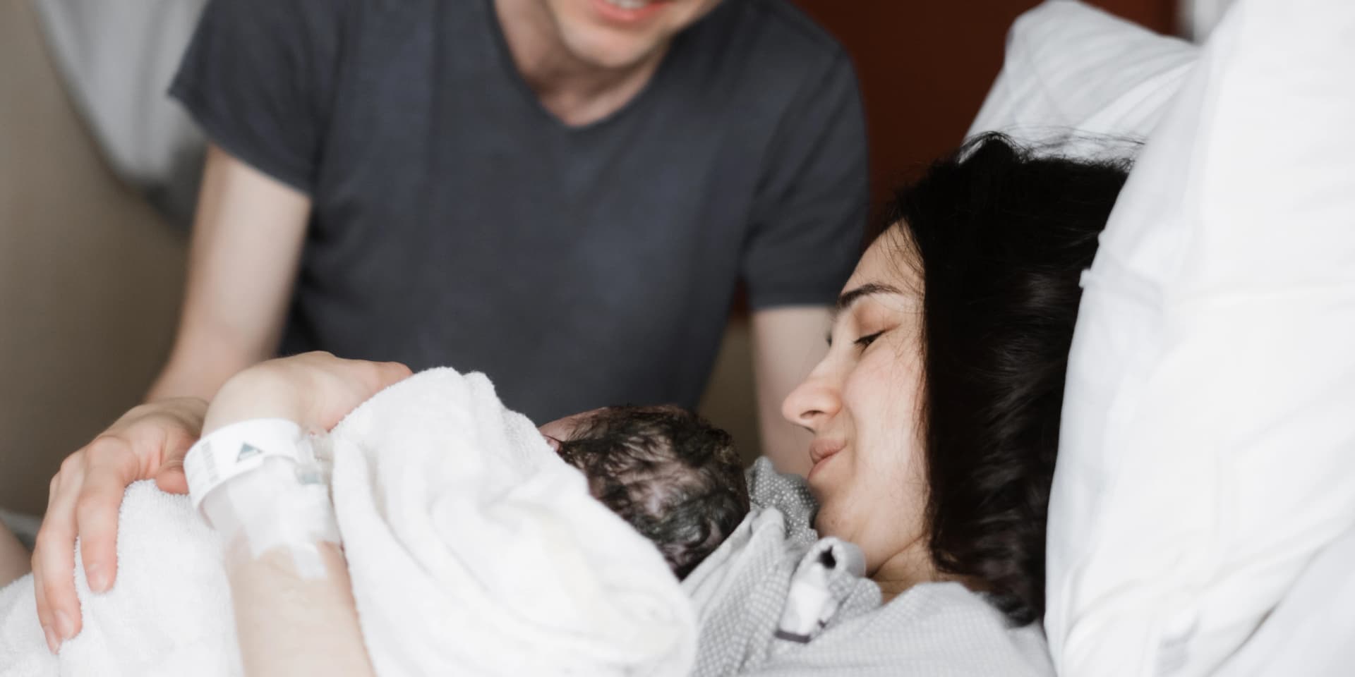 Mama und Papa begrüßen das Baby nach der Entbindung. Das Neugeborene liegt bei der Mutter auf der Brust.