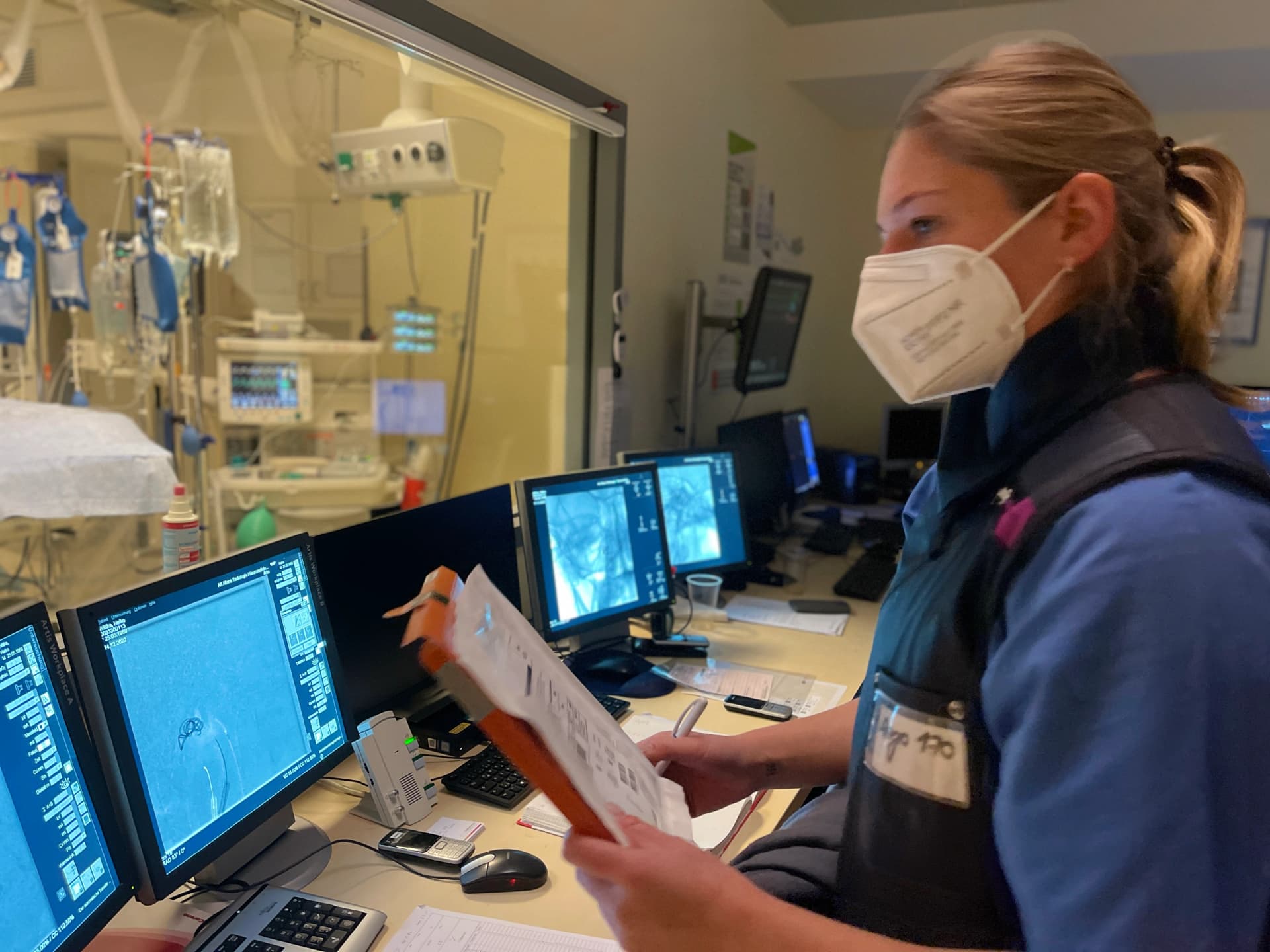 MTR-Kollegin ist im Kontrollraum der Angiografie und behält die Patient:innen im Blick.