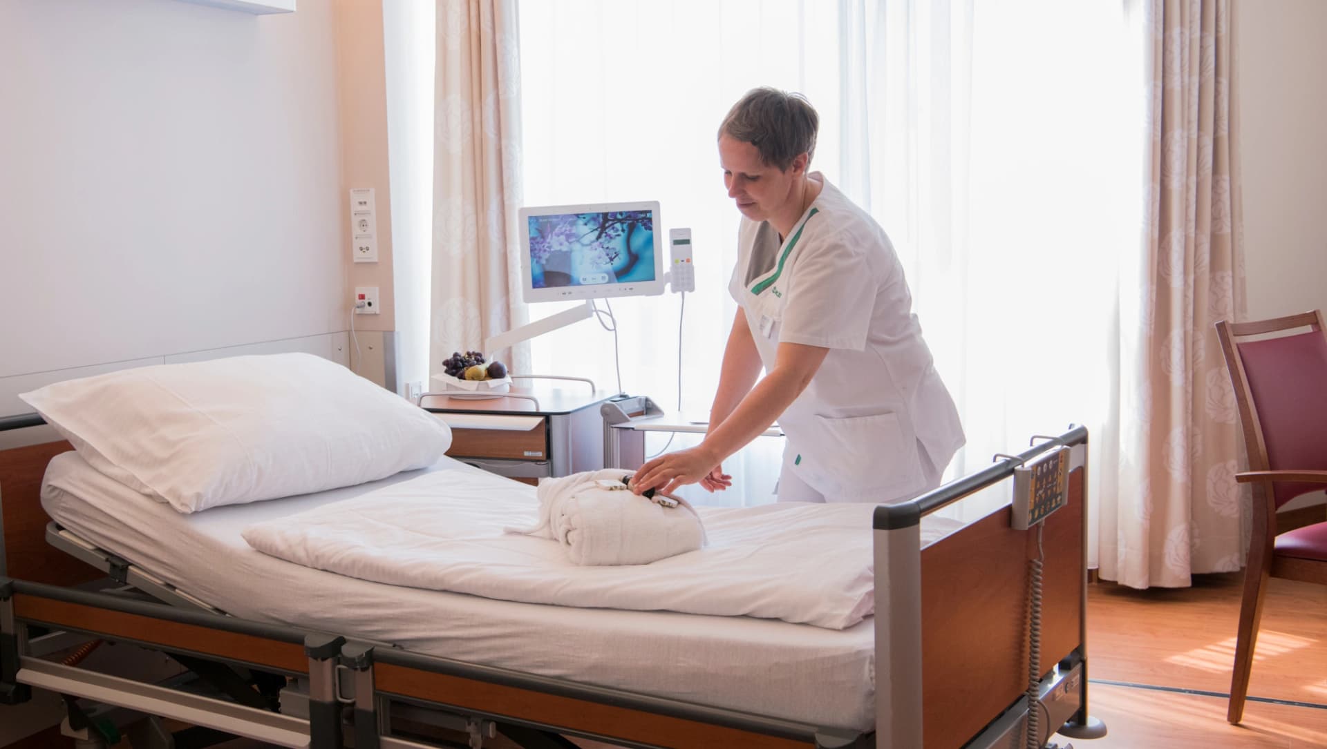 Das Bild zeigt einen Pflegekraft, die eine Bett auf der Privatstation richtet