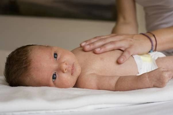 Unsere Ostepathin führt bei einem Baby, das auf dem Rücken liegt, einen sanften Check-up durch – denn die Geburtskräfte können sich auf jedes Kind anders auswirken.