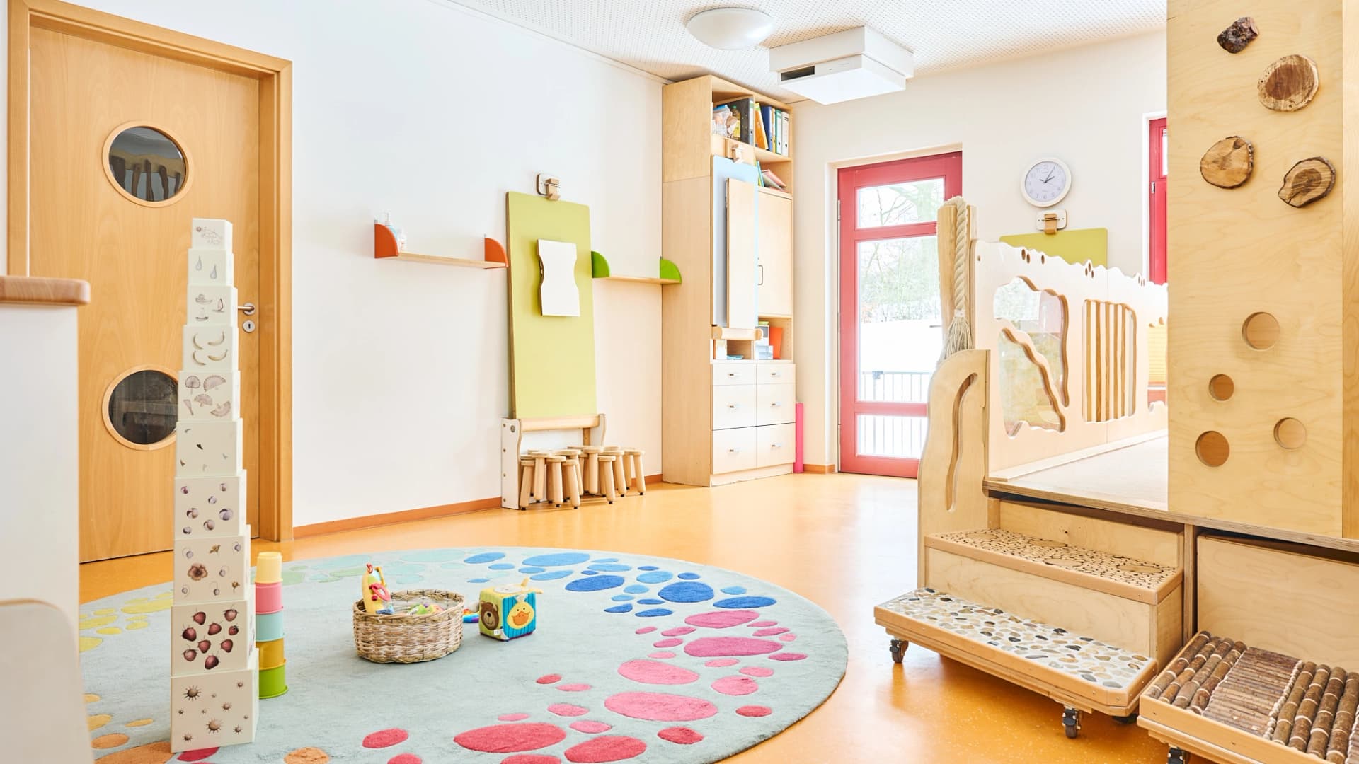 Bild: Gruppenraum mit Spielstationen und Sensorikelementen zur Förderung selbstständiger Aktivitäten.