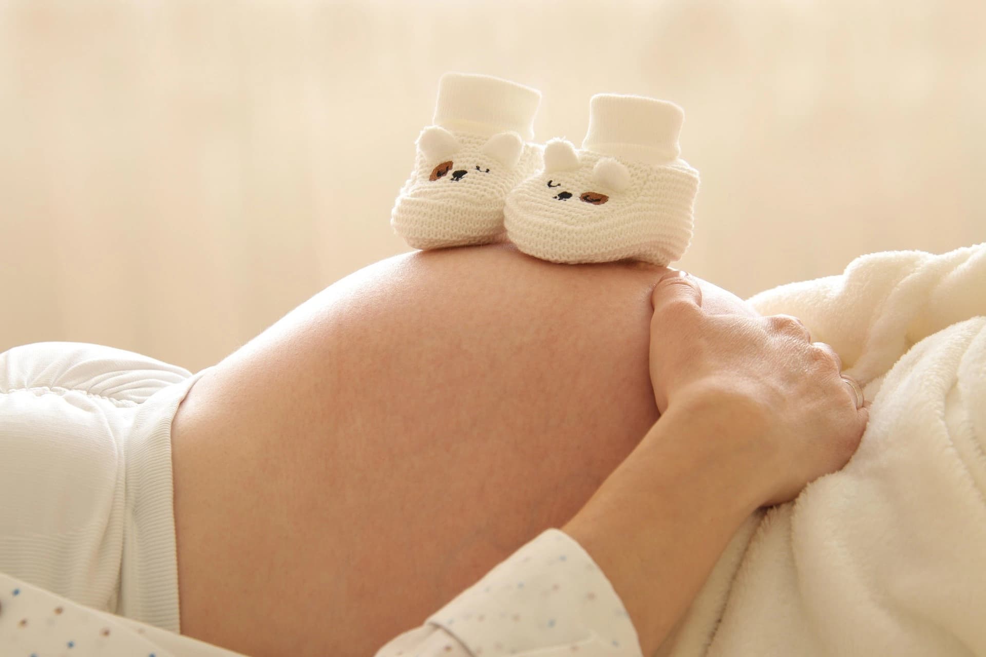 Schwangere Frau mit kleinen Babyschuhen auf dem Babybauch