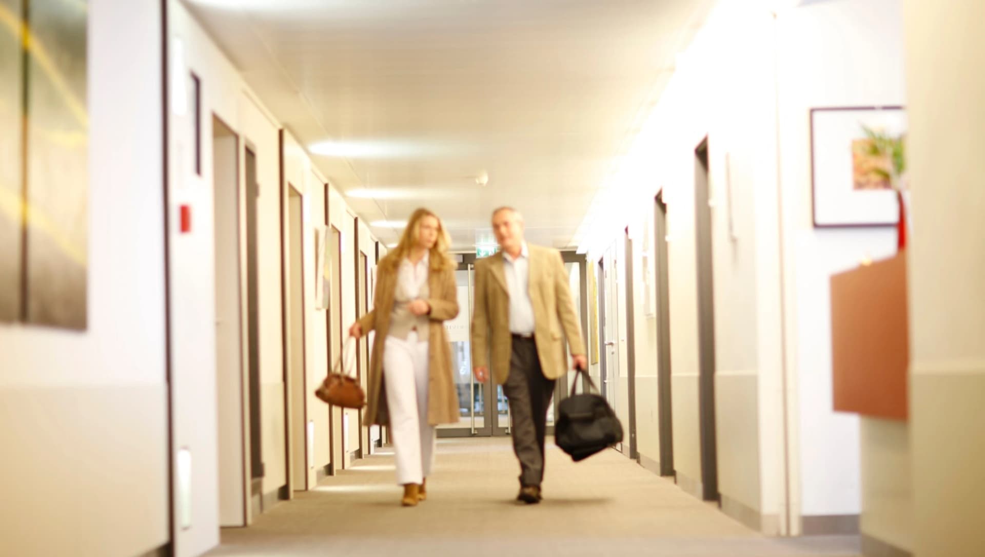 Das Bild zeigt ein PAr, das mit gepackter tasche ienenKlinikgang entlang läuft