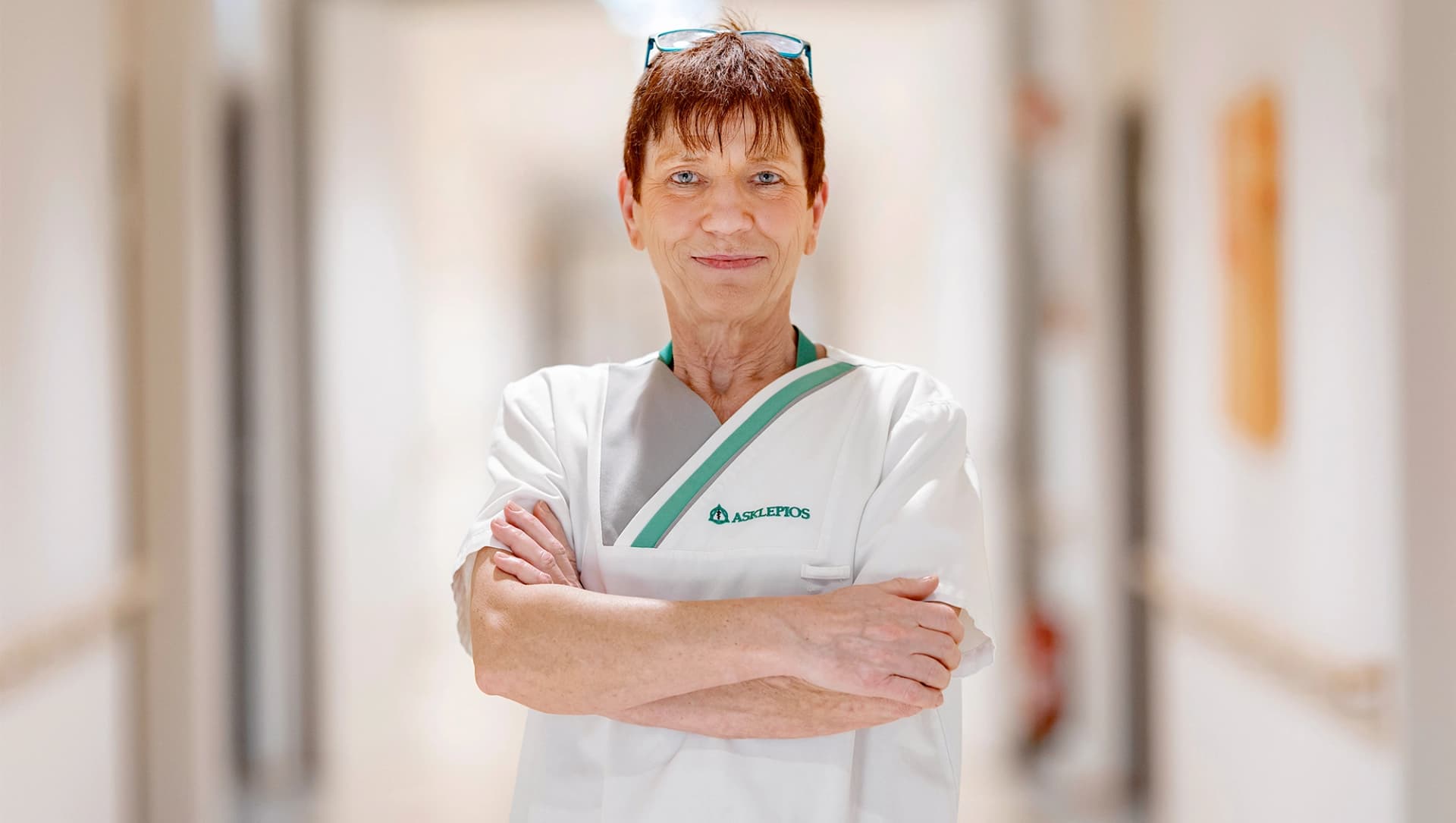 Eine Pflegekraft steht auf dem Flur mit lächelndem Blick