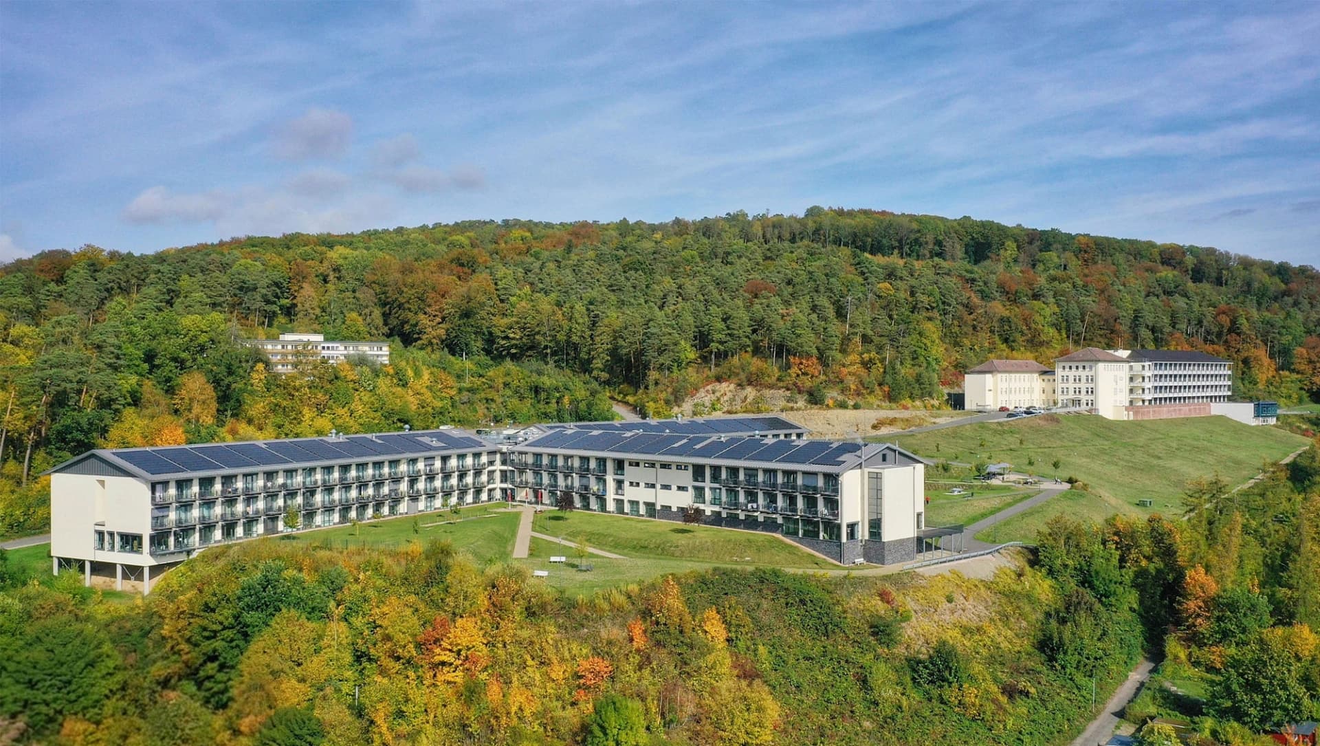 Beide Klinikbereiche der AWBK sind zu sehen, rundherum ist viel Wald und Wiese