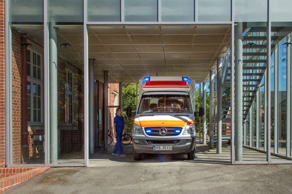 Auf dem Foto ist ein Krankenwagen mit eingeschaltetem Blaulicht, vor der Zentralen Aufnahme stehend.