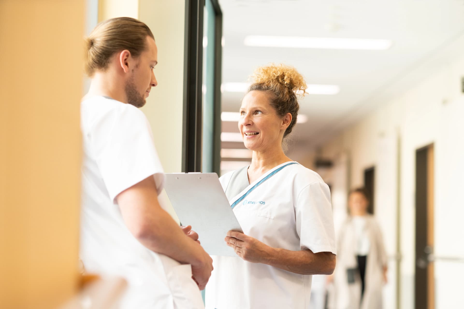 Bild: Asklepios-Mitarbeiter:innen unterhalten sich im Klinikflur