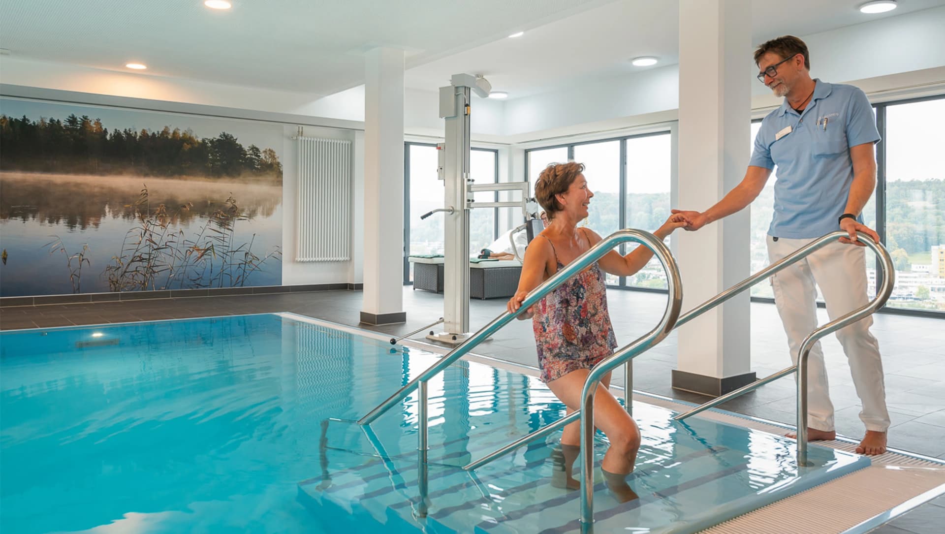 Ein Mitarbeiter hilft einer Patientin aus dem Bewegungsbad