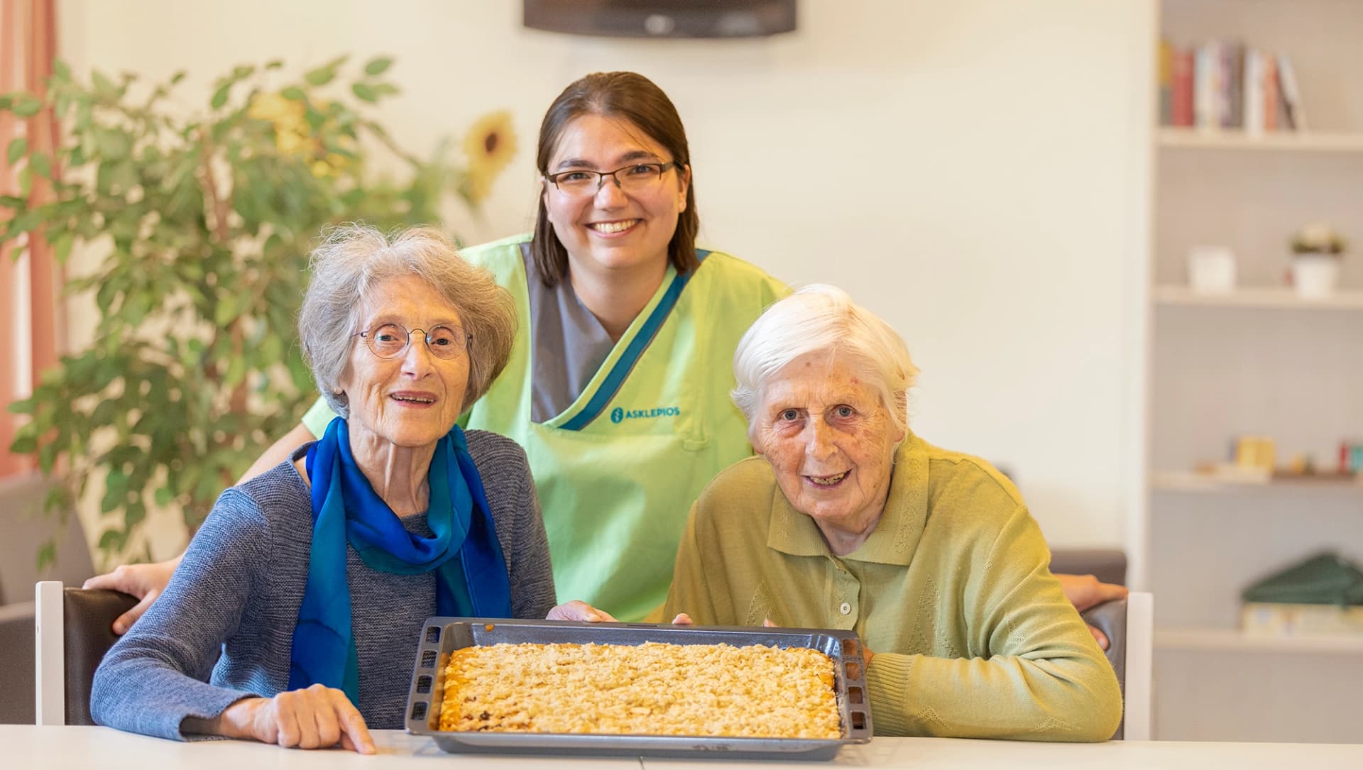 Zwei Patient:innen und eine Therapeutin zeigen ihren selbst gebackenem Apfelkuchen