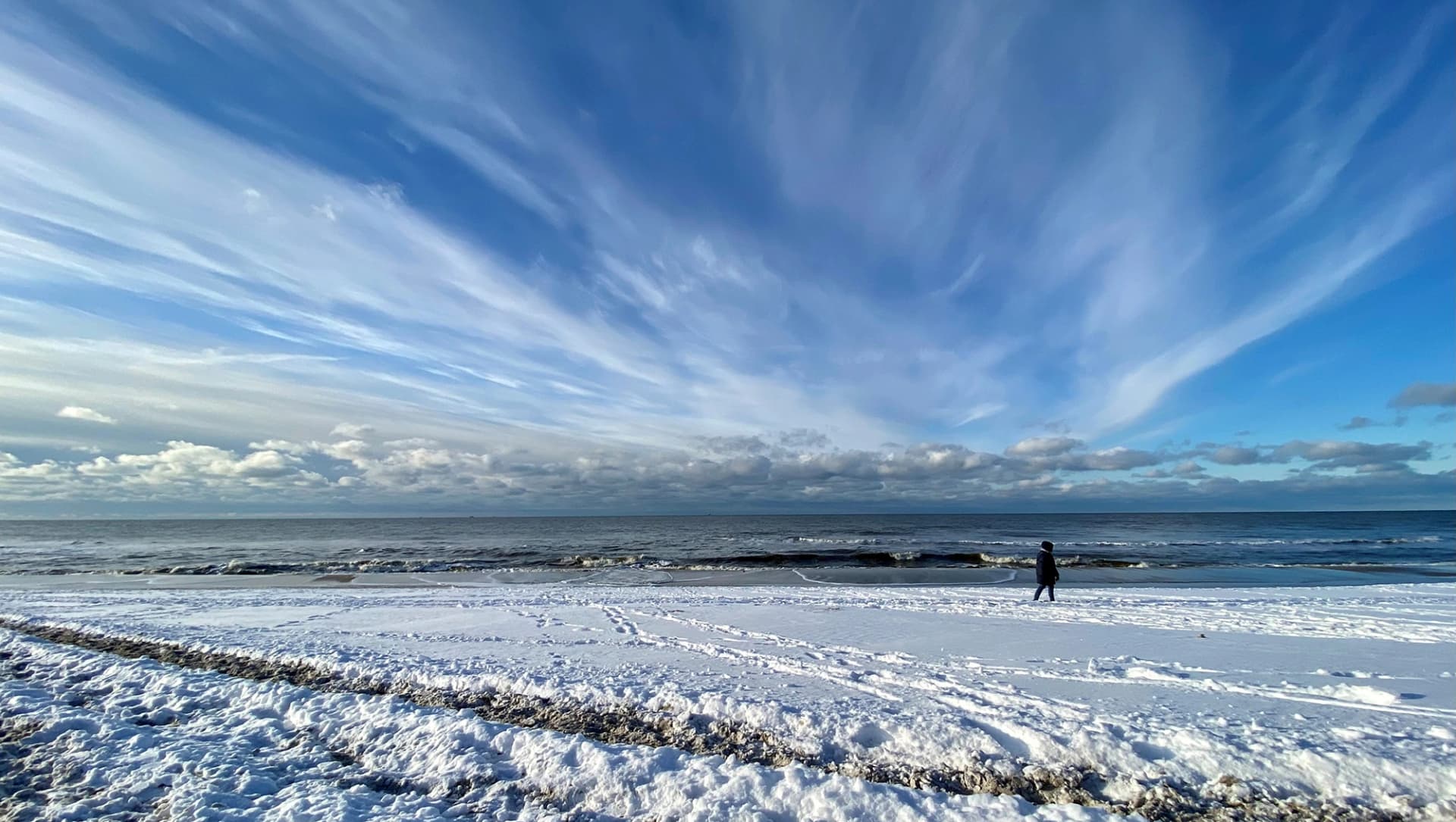 Das Motiv zeigt den Strand mit Schnee und blauem Himmel.