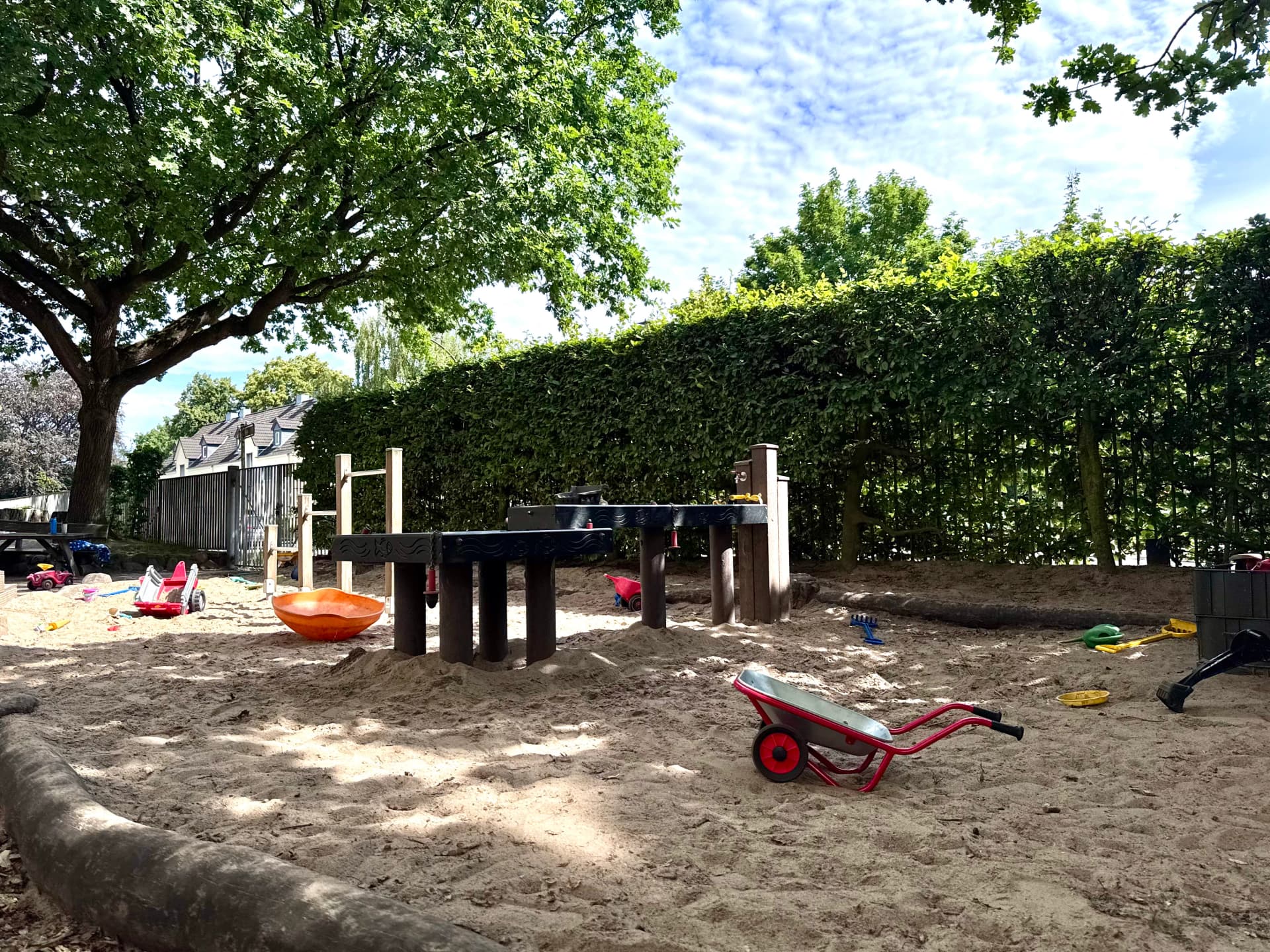 Bild: Sandkasten mit Spielzeugen und Bäumen