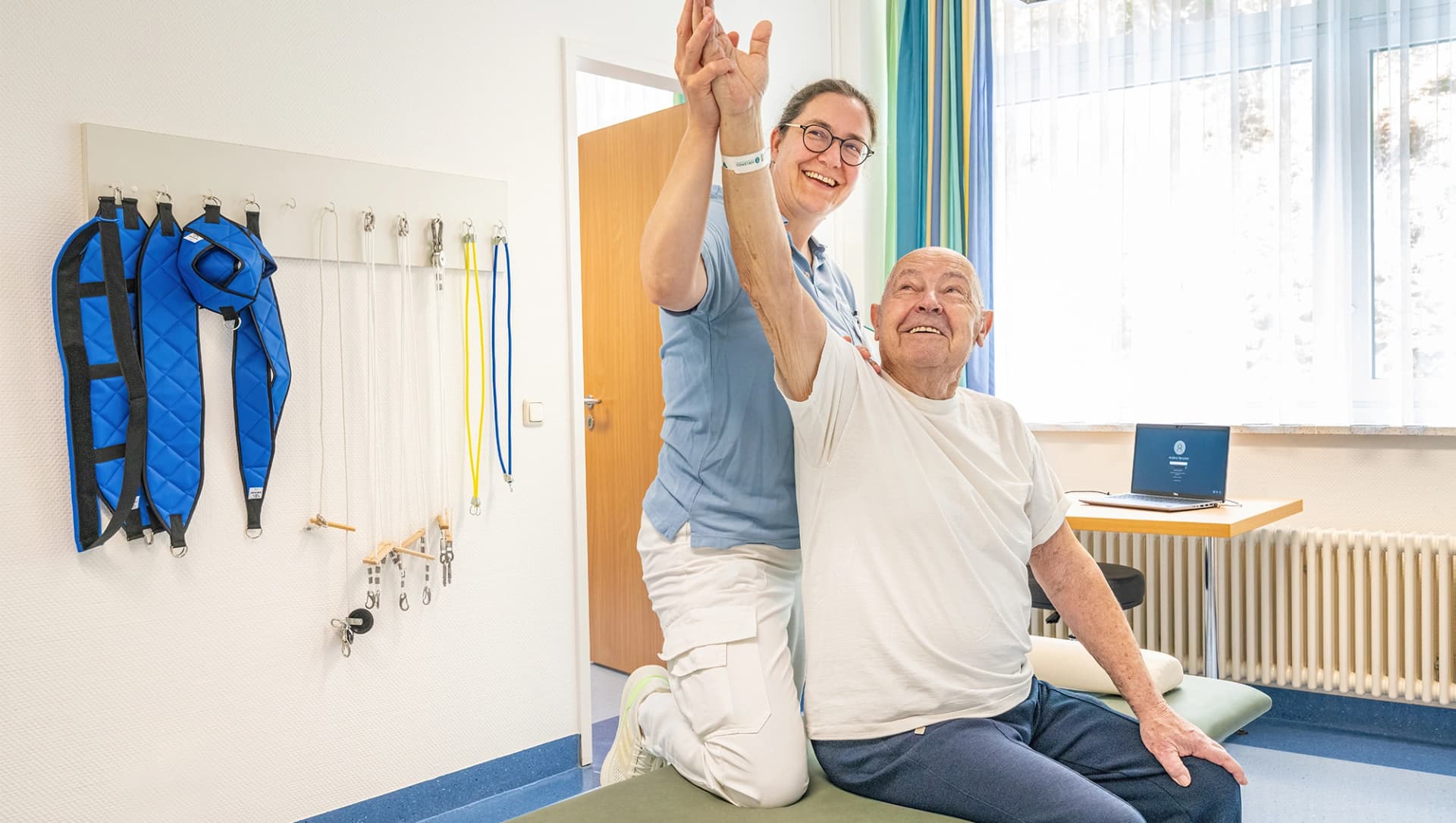 Physiotherapeutin macht Übungen mit einem Patienten auf einer Therapieliege