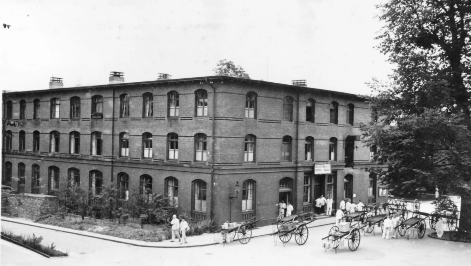 Das Foto zeigt das Küchengebäude des Allgemeinen Krankenhauses St. Georg. Im Vordergrund stehen Handwagen zur Verteilung der Speisen durch Transporteure.