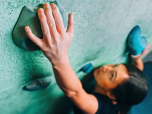 Bild: Frau beim Klettern an der Kletterwand