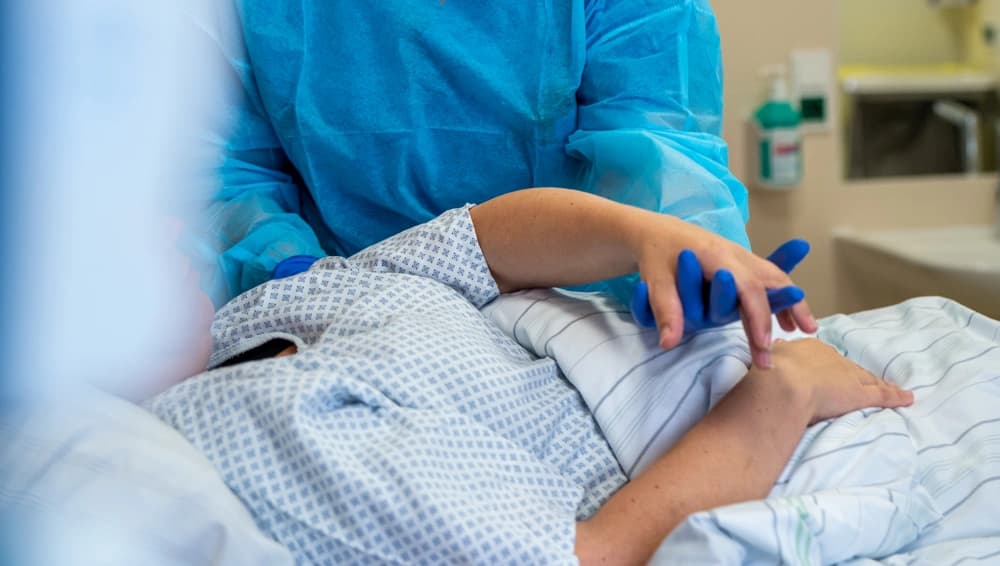 Das Bild zeigt eine Pflegerin, die die Hand eines Patienten fürsorglich hält.