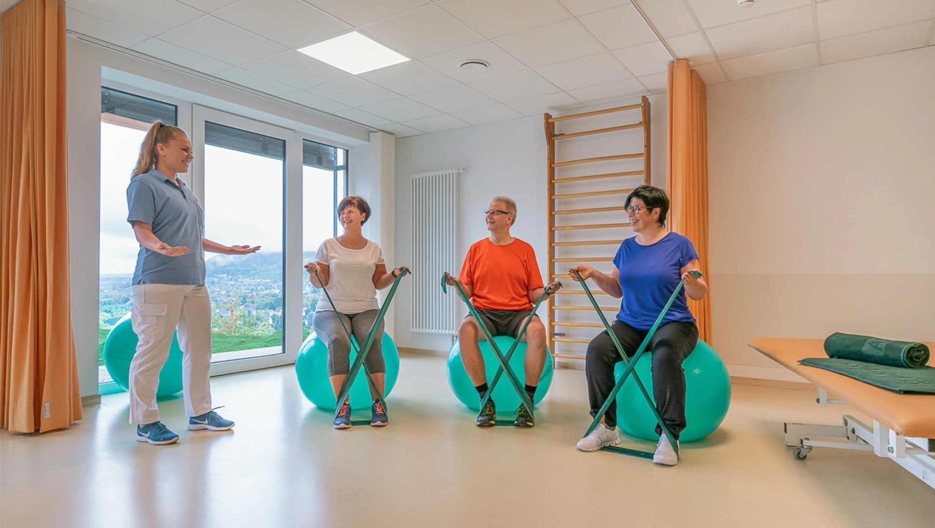 Patienten sitzen auf Gymnastikbällen und haben Terrabänder in den Händen