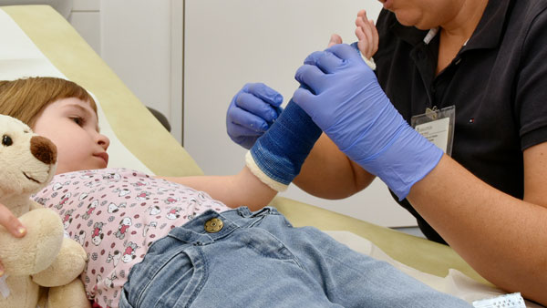 Kind und Ärztin beim Gipsen Kind mit Unterarmgips