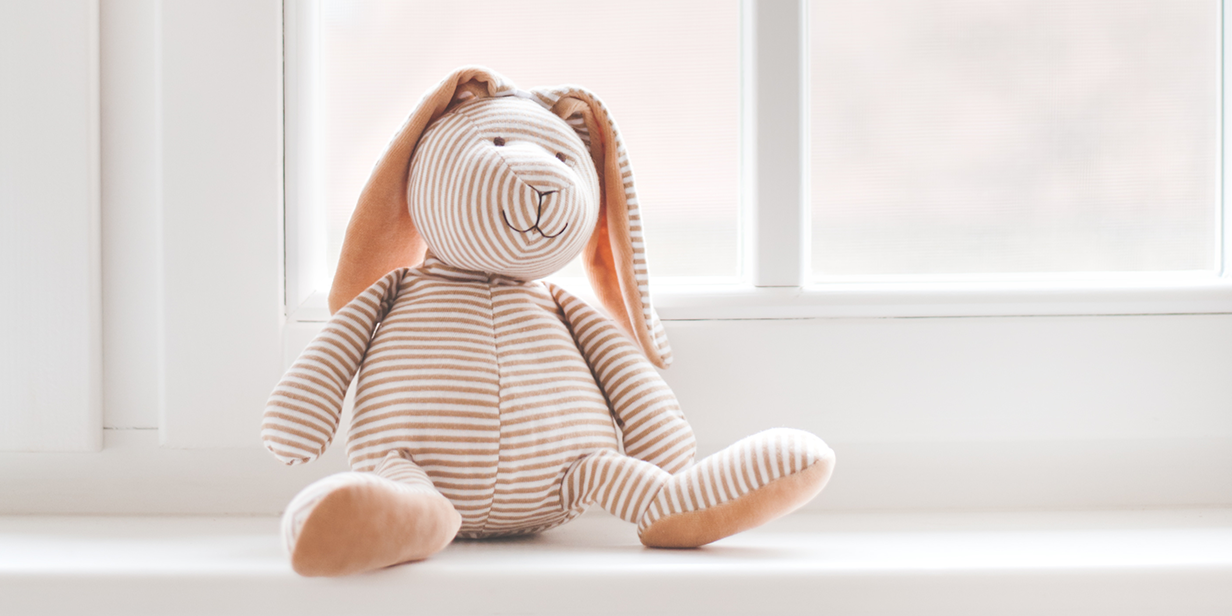 Stoffhase vor Fenster Ein gestreifter Stoffhase sitzt vor dem Fenster auf der Fensterbank