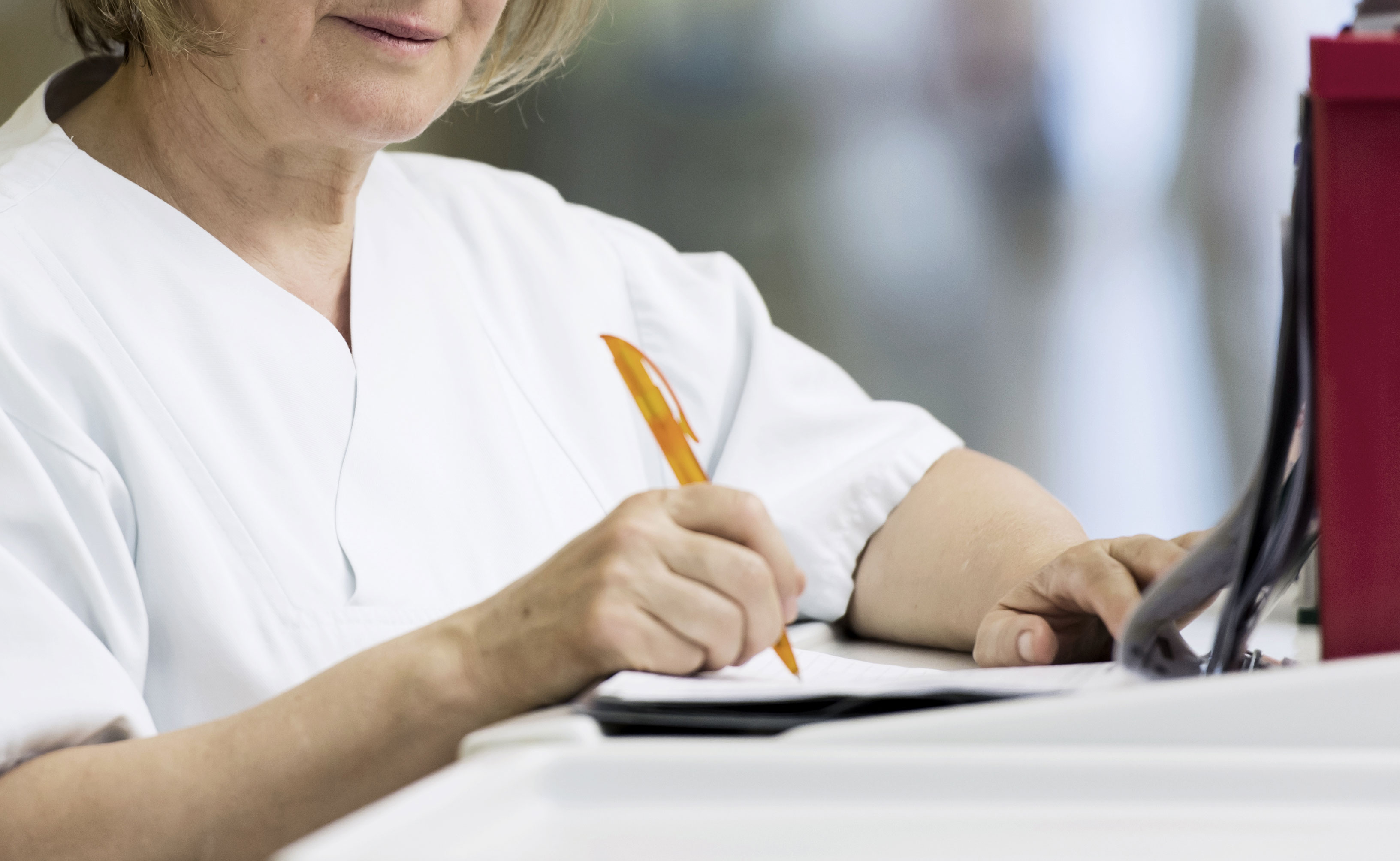 Pflegerin schreibt in Patientenakte Bild: Pflegerin schreibt in Patientenakte