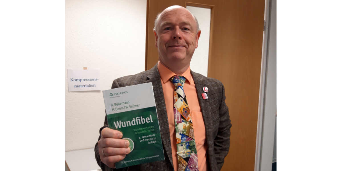 Wundexpertenkurs Bild: Kursleiter Werner Sellmer mit Wundfibel