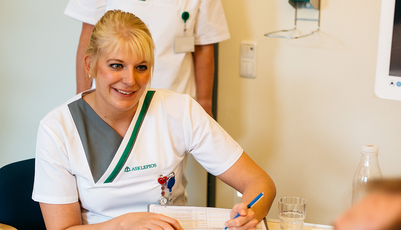 Eine Pflegefachfrau füllt mit einem Patienten einen Anamesebogen aus Eine Pflegefachfrau füllt mit einem Patienten einen Anamesebogen aus