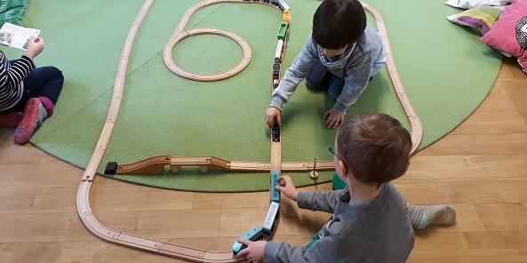 Kinder mit Holzeisenbahn Bild: Kinder bewegen zwei Züge aufeinander zu