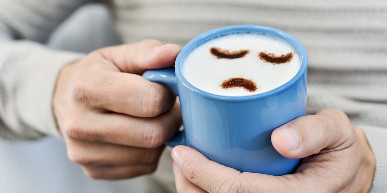 Tasse mit traurigem Smiley Eine Tasse mit traurigem Smiley wird in der Hand gehalten