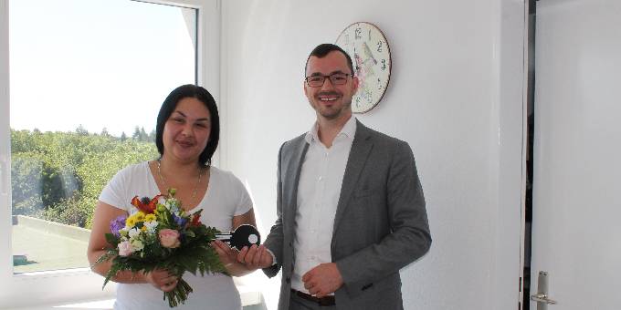 wohnungsübergabe mexikoring inhalt bild: der geschäftsführende direktor sebastian von der haar übergibt blumen und einen symbolischen schlüssel an jelena gajs.