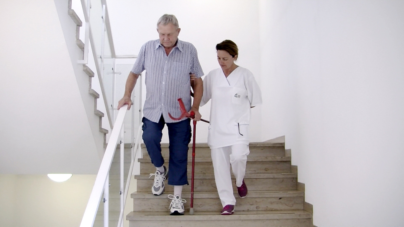 Physiotherapeutin mit Mann auf Treppen Bild: Physiotherapeutin übt mit Mann Treppen zu laufen